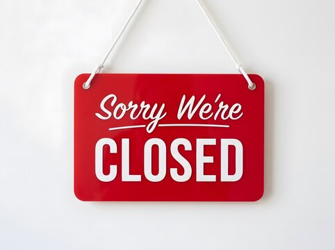 Red hanging sign with 'Sorry We're CLOSED' message in white letters against a plain white wall