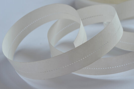 Close up of vintage white paper punched tape, early computer data storage and teleprinter medium