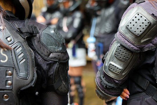 Armored protective gear and elbow pads on riders preparing for outdoor sports event, gritty texture and focused teamwork energy