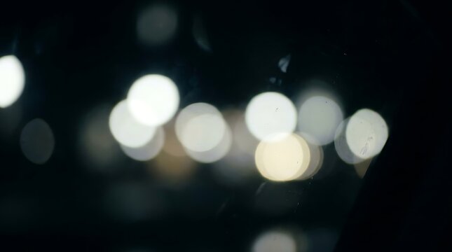 Blurred city lights creating glowing bokeh effect at night street scene for festive background usage.
