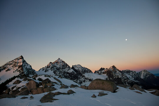 Snowy mountain peaks glowing at twilight with moon