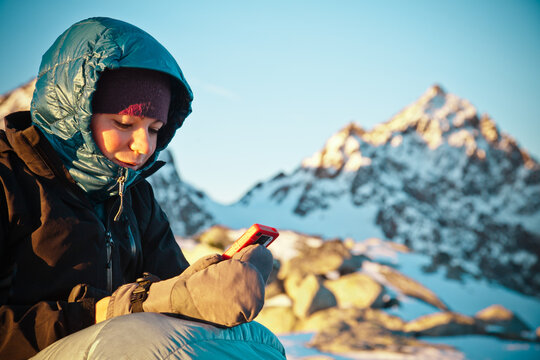 Woman checks GPS device on a snowy mountain peak
