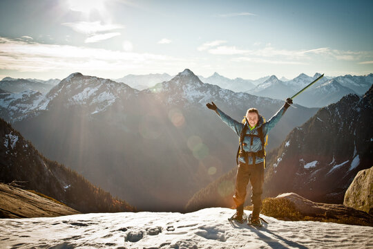 Joyful woman raises arms on snowy mountaintop
