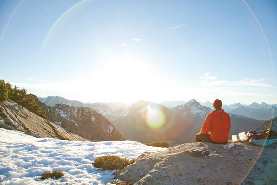 Hiker rests on snowy summit enjoying mountain view