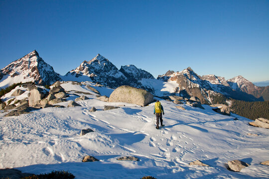 Hiker snowshoeing across a snowy mountain landscape