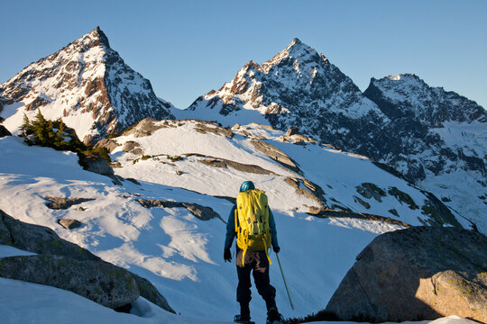 Hiker views snowy mountain peaks at sunrise