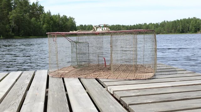 Net and box to catch fish at a lake. Fishing kit. Ready to use, at a wooden bridge. Summer day in July. Eken&auml;s, Finland.