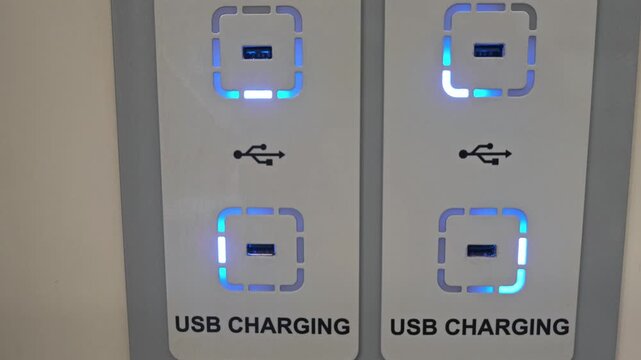 Row of USB charging sockets with glowing blue lights on a panel in a public area, reliable power access, modern connectivity, travel amenity, smart city.