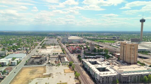 The drone flies toward the distinctive dome shaped Alamodome stadium within the downtown skyline.