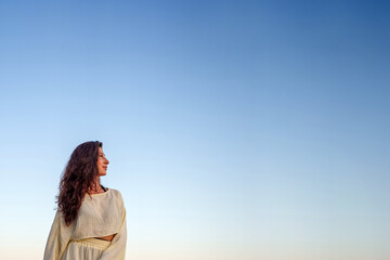 Naklejka premium Woman with curly hair looking confidently towards new horizons, contemplating future under clear open blue sky