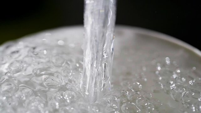 Close up macro of a running dripping tap. Water flowing and bubbling. Tap water silver kitchen fixtures,