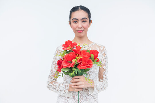 A young Filipino bride in an elegant lace wedding gown holds a bouquet of red roses and looks confidently toward her wedding day.