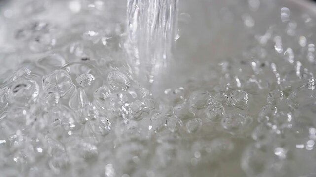 Close up macro of a running dripping tap. Water flowing and bubbling. Tap water silver kitchen fixtures,