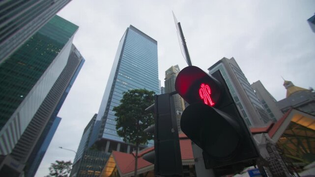 A close-up of a traffic light showing a red signal for pedestrians. An urban scene featuring road traffic and a prohibition on crossing the street.