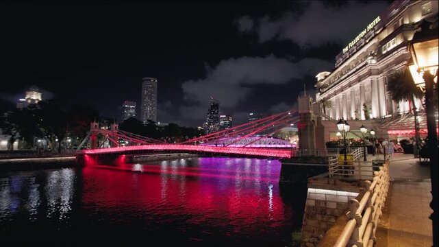 Beautiful illuminated Cavenagh Bridge spanning the Singapore River with stunning night cityscape and vibrant metropolitan skyline attracting travelers across Asia 