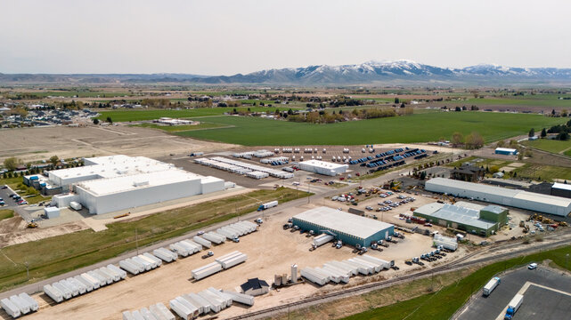 Aerial view of a warehouse complex with rows of storage containers and mountains beyond.