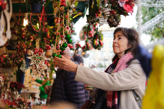 Senior woman buying christmas ornaments at market in barcelona