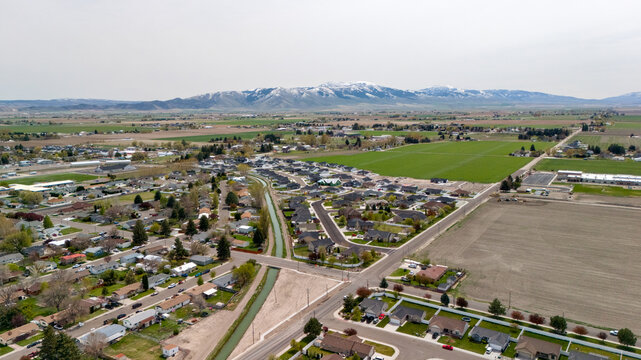 Aerial view of a residential cul de sac neighborhood with mountains and fields nearby.