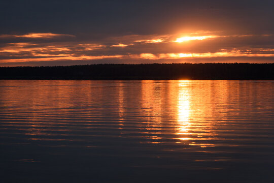 Dramatic Sunrise over Calm Lake with Golden Water Reflection