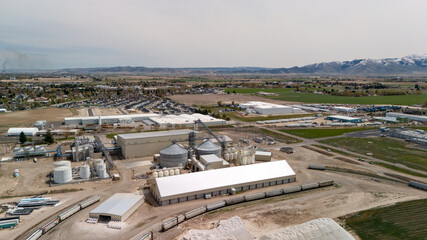 Aerial view of a long industrial warehouse with grain silos and a mountain range beyond. © Moiseii Production