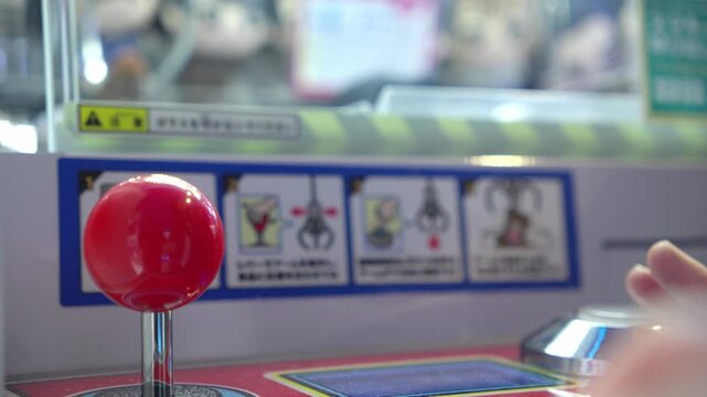 Person's hand operating a claw machine joystick