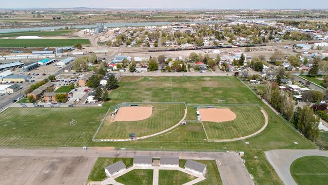 Aerial view of baseball diamonds in a small town park surrounded by trees and homes.