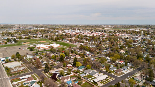 Aerial view of a small town center with a school, parking lots, and tree lined streets.