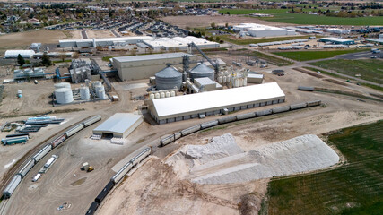 Aerial view of an industrial complex with grain silos and a curved railway line. © Moiseii Production