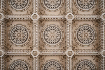 Obraz premium Ornate architectural ceiling with symmetrical square panels featuring circular floral carvings and decorative molding in a light beige color