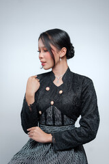 Profile portrait of an elegant Indonesian woman in a black lace kebaya and batik dress. © Saddha Visual