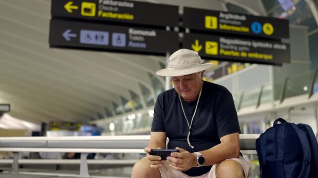 Mature tourist winning game on smartphone at airport