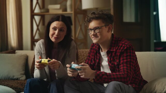 Happy mother and adolescent son playing a video game as a team, leisure activity