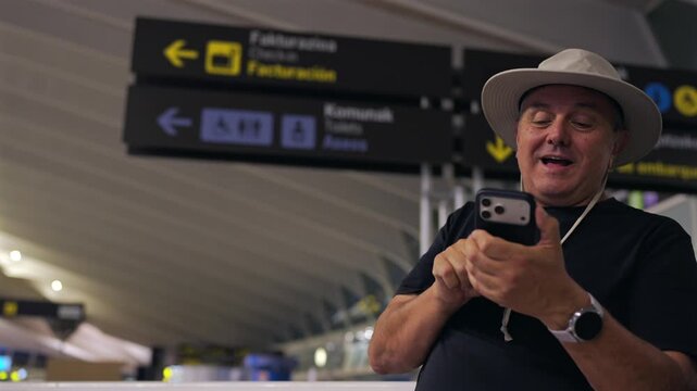 Senior man having a video call on a smartphone at the airport