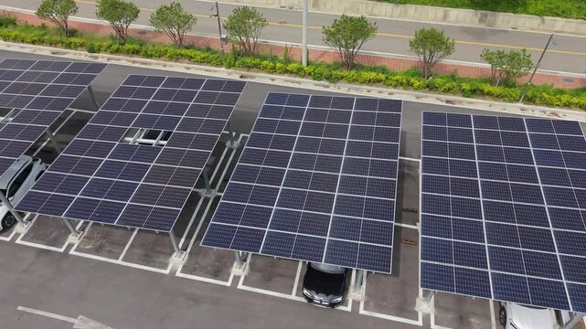 Aerial top-down view reveals rows of solar panel carports shading parked cars beside road and greenery