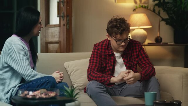 Adolescent boy listening to his annoyed mother scolding him, difficult phase