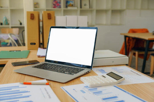 Laptop Blank White Screen Mockup on Office Desk with Financial Reports and Calculator.