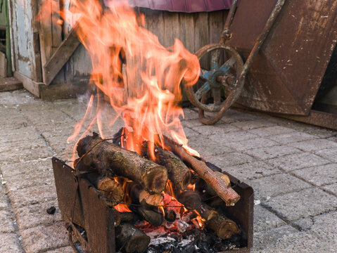 Bright Flames Burning Wooden Logs inside Metal Barbecue Grill Outdoors