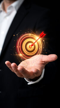 Hand reaching out towards floating bullseye with arrow representing success vision and achievement in goal oriented business strategy concept