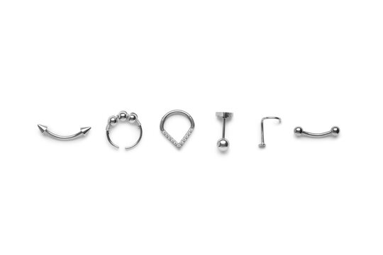Assortment of silver body piercing jewelry including barbells, rings, and studs, isolated on a clean white background