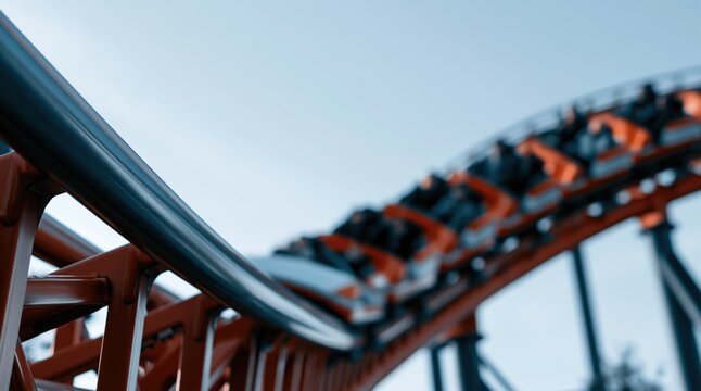 Low angle close up of roller coaster track with moving train against blue sky