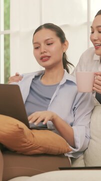 A caring woman brings a hot drink and gives a relaxing shoulder massage to her partner working on a laptop.