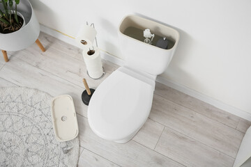Naklejka premium Toilet bowl with removed tank lid in light restroom
