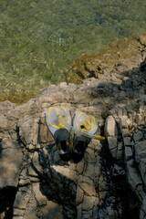 Snorkeling gear and flippers on a rocky shore by clear sea water © ShapeImages