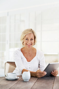 Smile, woman and relax at house with tablet, social media and browsing for weekend break. Portrait, mature person and coffee in home with digital, download ebook and reading news for morning routine