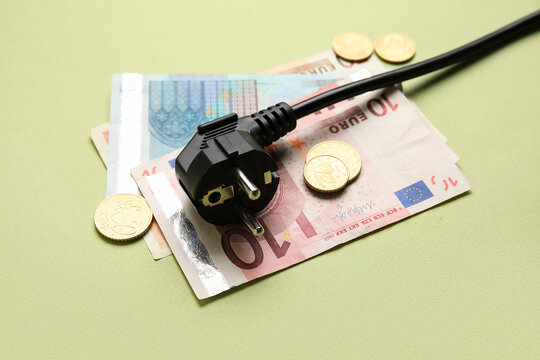 Electric power plug and money on green background