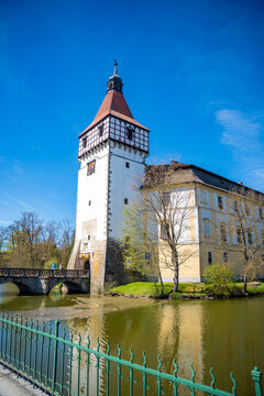 Blatna Castle reflected in the castle pond on a sunny spring day in Blatna, Czech Republic. Historic water castle architecture and landmark surrounded by park landscape