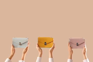 Fototapeta premium Female hands with different stylish womens bags on beige background