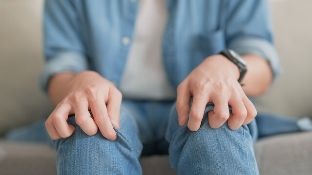 Closeup legs shaking in a guy in blue jeans. Uncontrollable leg shaking. Severe stress in a guy. A man is worried while sitting on a sofa. Health problems and sickness