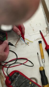 Electrician checking three phase power wires with probes vertical