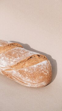 Artisan Bread Loaf: A close-up shot reveals a rustic, golden-brown artisan bread loaf, dusted with flour and casting a gentle shadow, evoking warmth and homemade goodness.